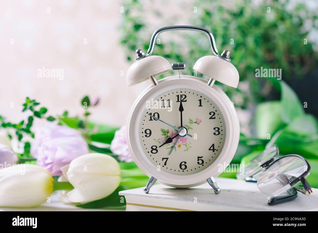 Spring flowers and retro Alarm Clock. Selective focus Stock Photo