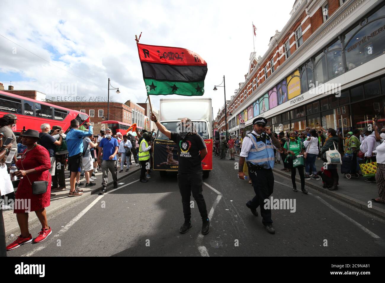 Protesters supporting the Stop the Maangamizi Campaign and the Afrikan Emancipation Day Reparations March Committee take part in a march from Windrush Square to Max Roach Park in Brixton, London. A curfew and other restrictions were imposed on demonstrations planned in south London to stop people blocking main roads or planning illegal music events, Scotland Yard has said. Stock Photo