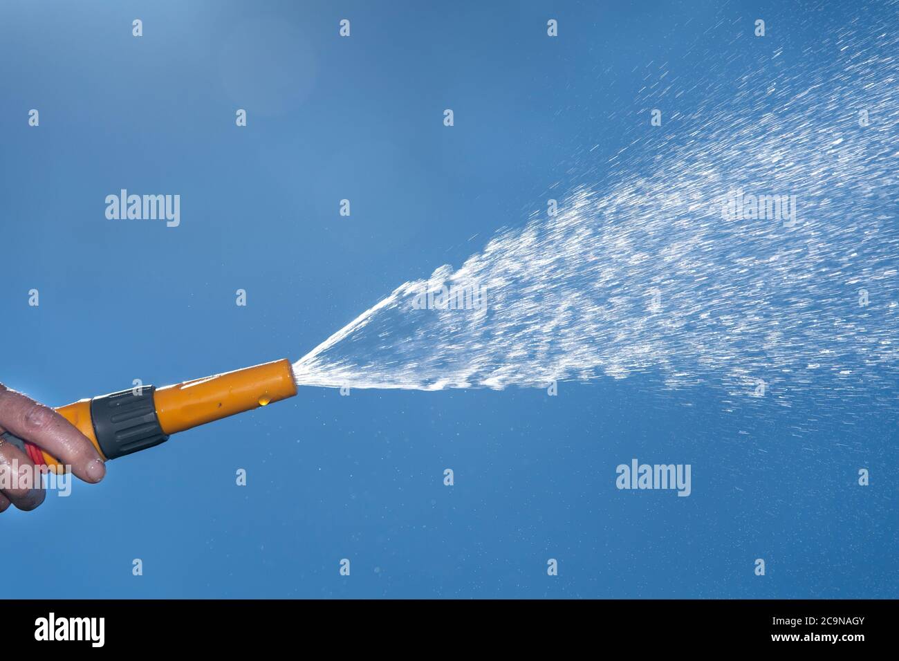 Water from a hose pipe being sprayed under pressure, against a blue summers sky. North Yorkshire, UK. Stock Photo