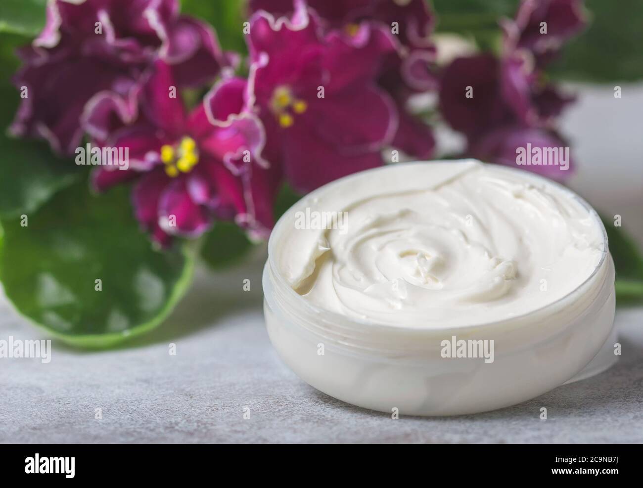 Cosmetic cream and red flowers. Selective focus Stock Photo