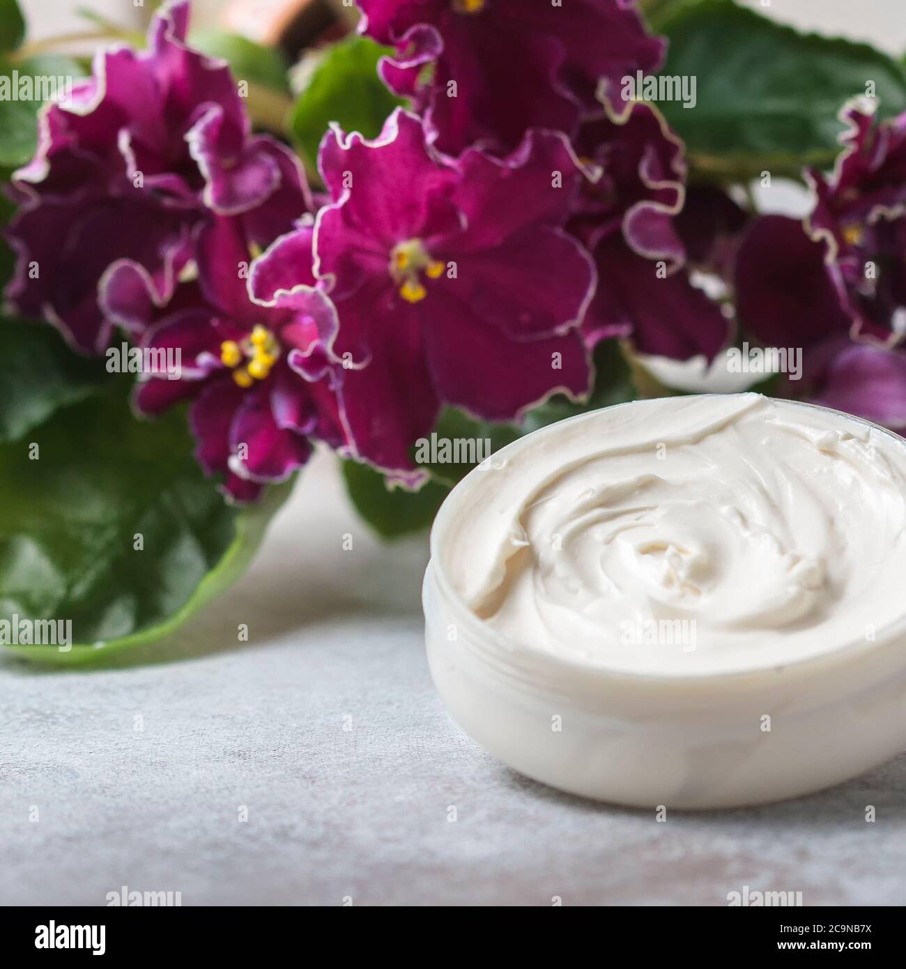 Cosmetic cream and red flowers. Selective focus Stock Photo