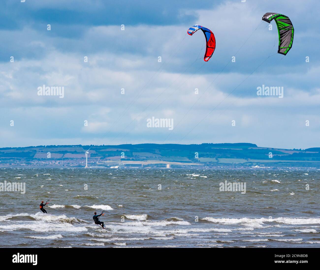 Kite surfers kite boarding on windy day with colourful kites, Firth of