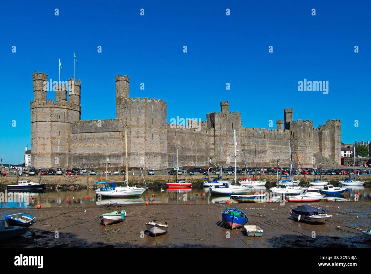 Caernarfon Castle Welsh medieval historical stone fortress building on River Seiont boats in landscape UNESCO heritage tourism Gwynedd North Wales UK Stock Photo