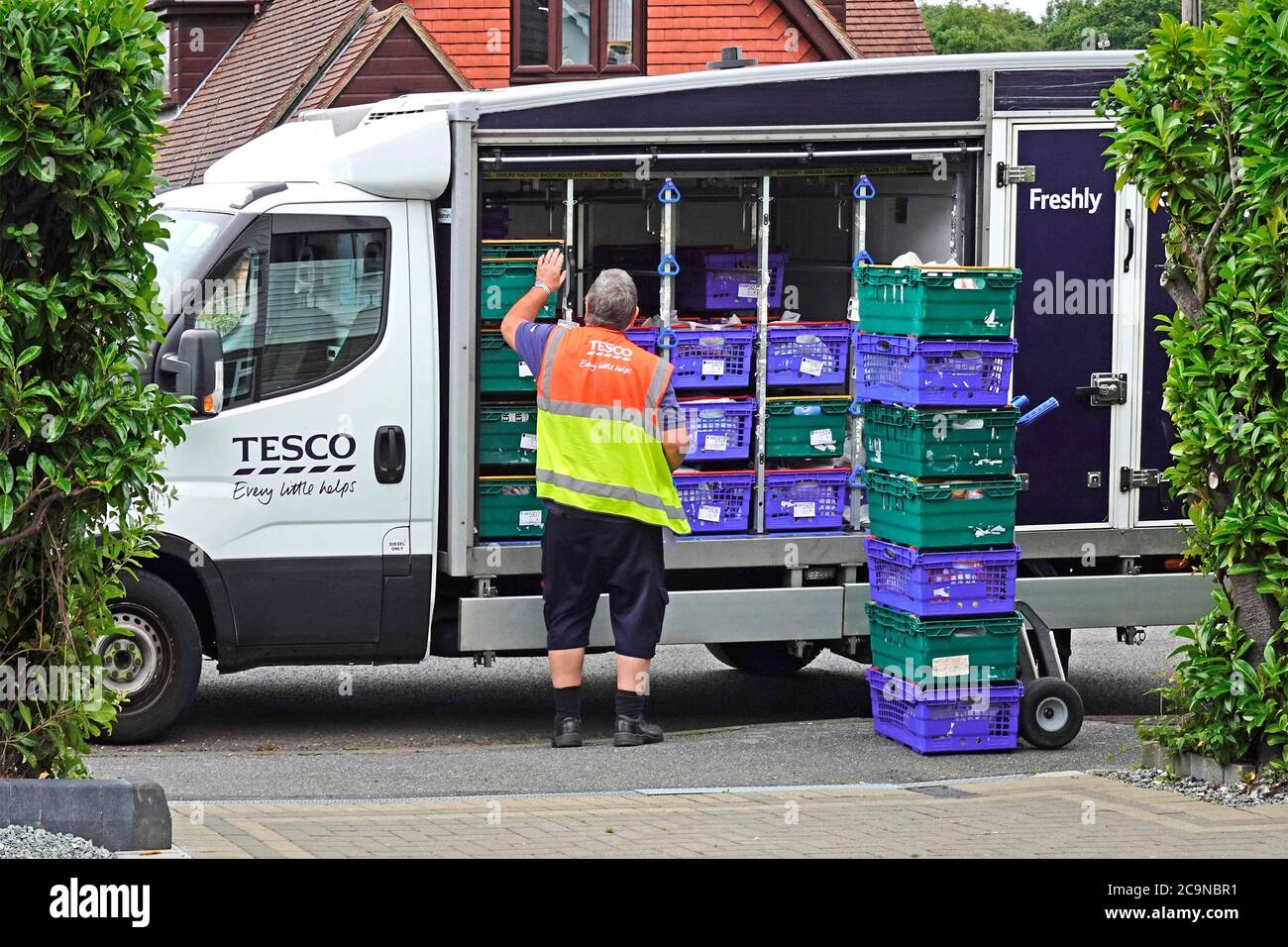 Supermarket online internet supply chain home food grocery shopping delivery on Tesco van driver loads onto trolley at customer home Essex England UK Stock Photo