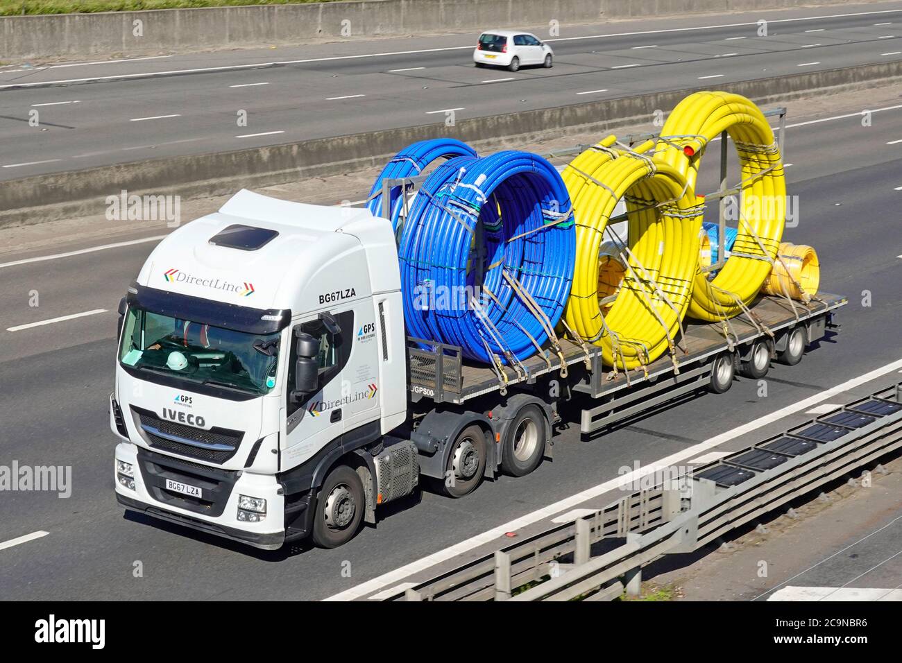 GPS PE plastic pipe business supply chain Iveco hgv lorry truck & low loader trailer load of coil yellow gas & blue water polyethylene tube England UK Stock Photo