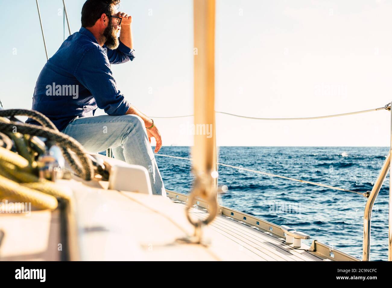 Adult man enjoy outdoor leisure activity sit down on a sail boat looking blue ocean and sky - concept of travel and freedom during summer holiday vaca Stock Photo