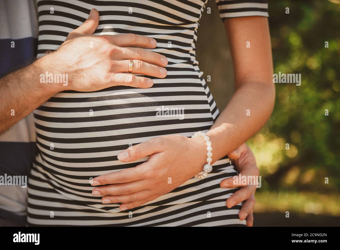 Close up portrait of happy pregnant woman together with husband hugging in summer park Stock Photo