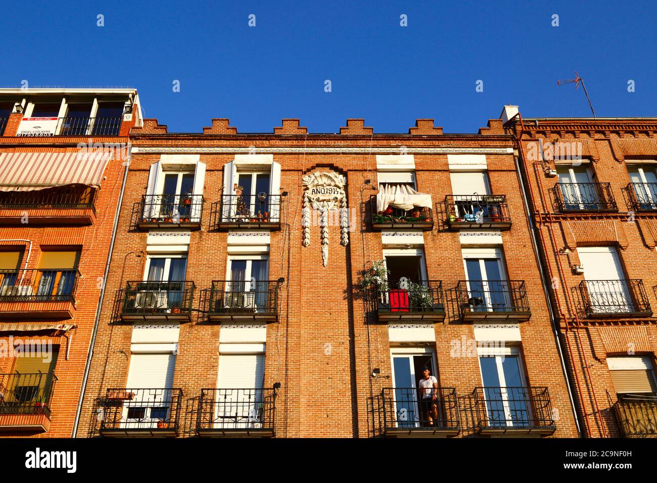 Man on balcony of apartment building dating from 1914 on Calle del Rosario near Plaza San Francisco, Imperial district, Madrid , Spain Stock Photo
