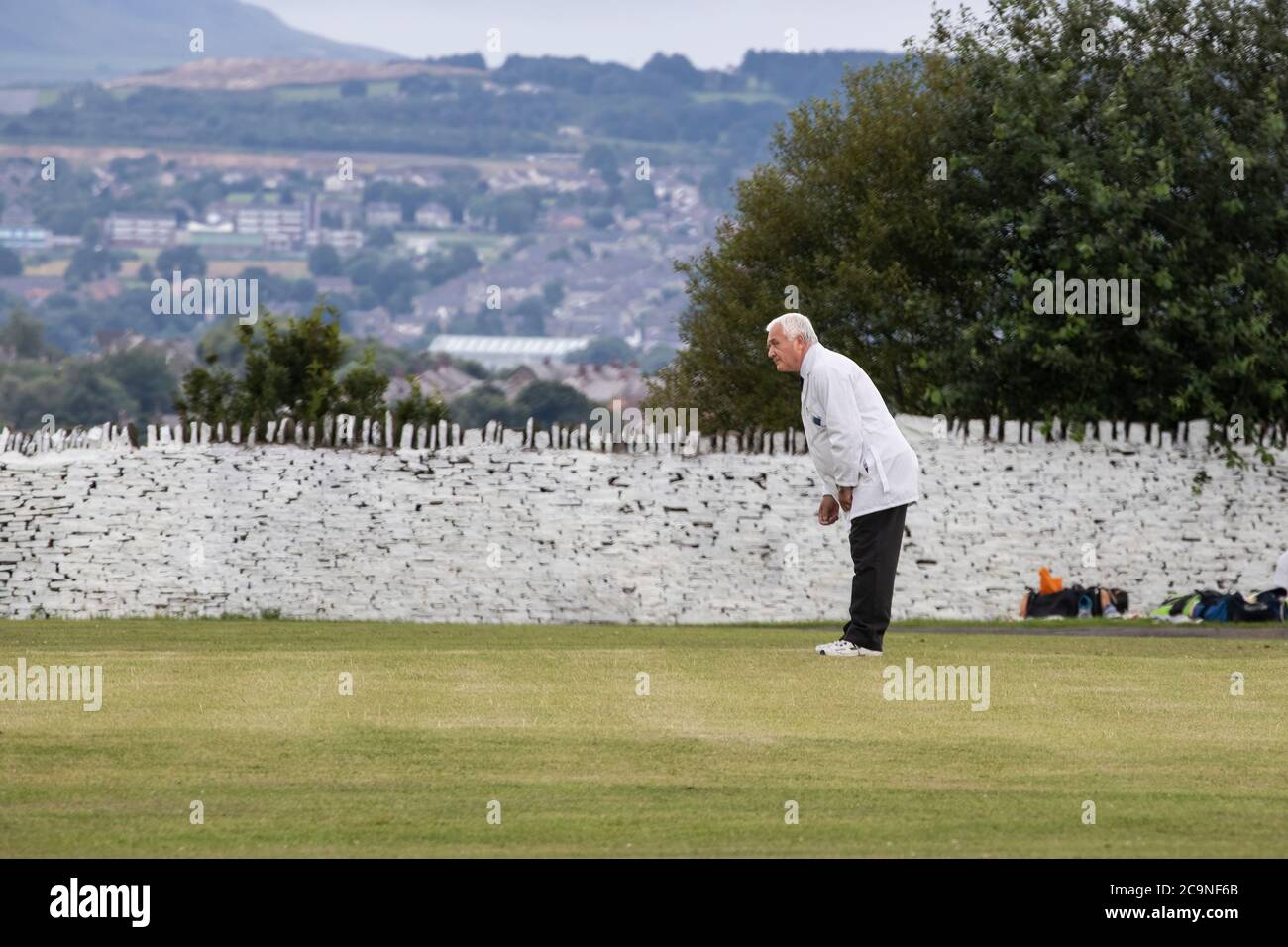 Umpire in a cricket match dressed in a traditional white coat