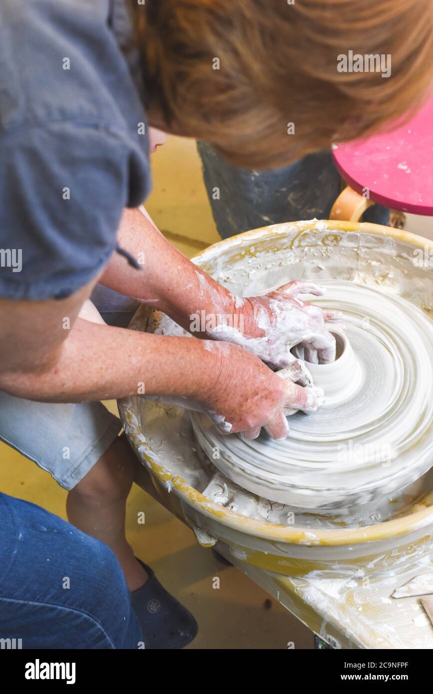 Children learning to make pottery as a hobby with their grandmother in