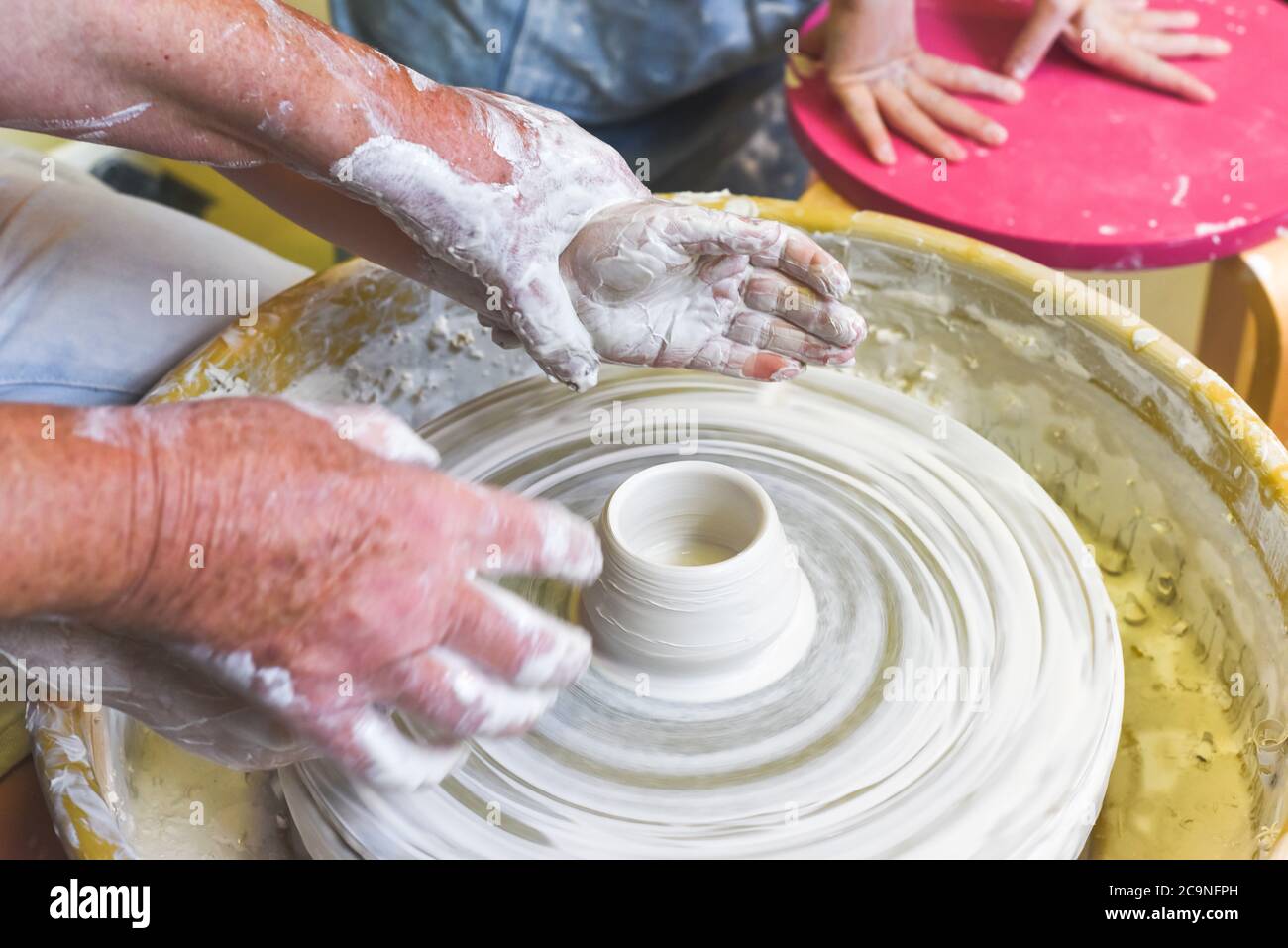Children learning to make pottery as a hobby with their grandmother in