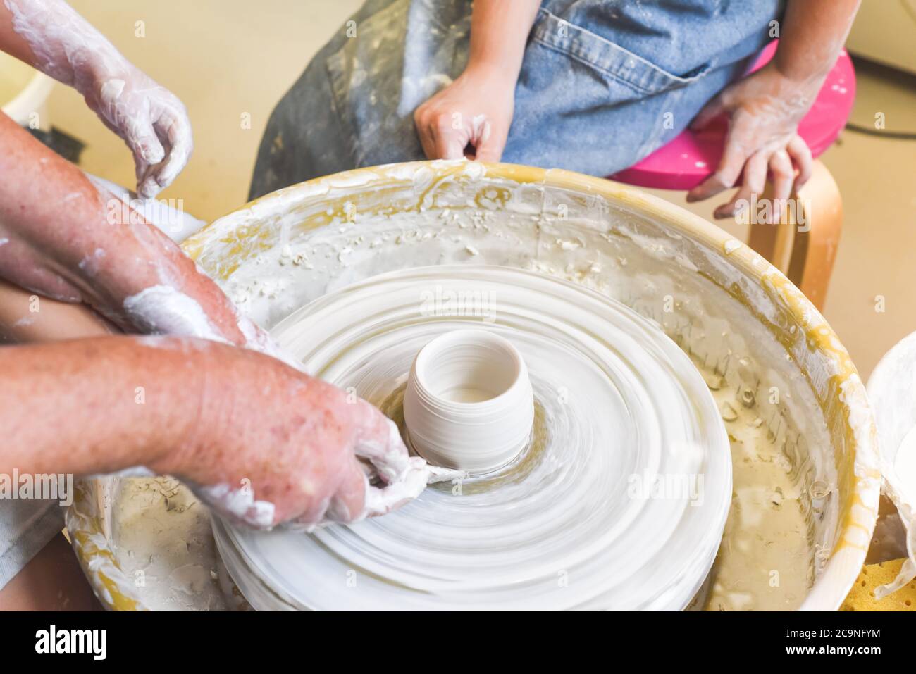 Children learning to make pottery as a hobby with their grandmother in