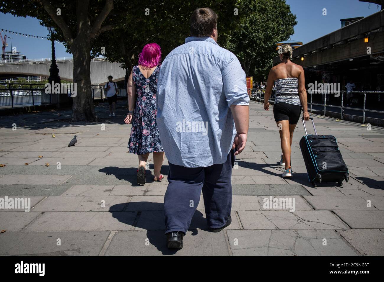 Obese man walks along South Bank, central London, United Kingdom. Being male or overweight can lead to more serious COVID-19 hospital admissions, UK Stock Photo