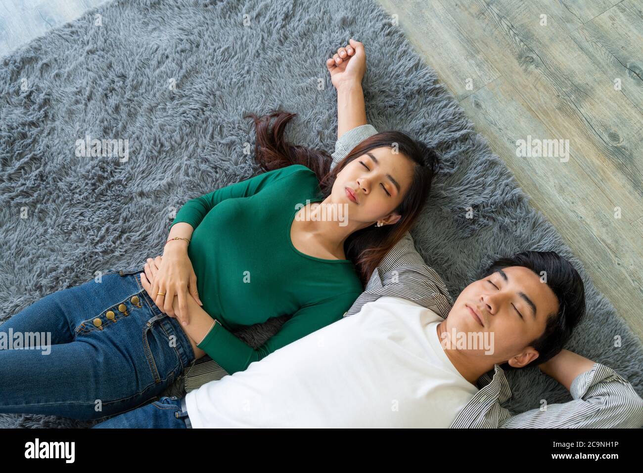 Happy Asian couple lying together on carpet Stock Photo - Alamy