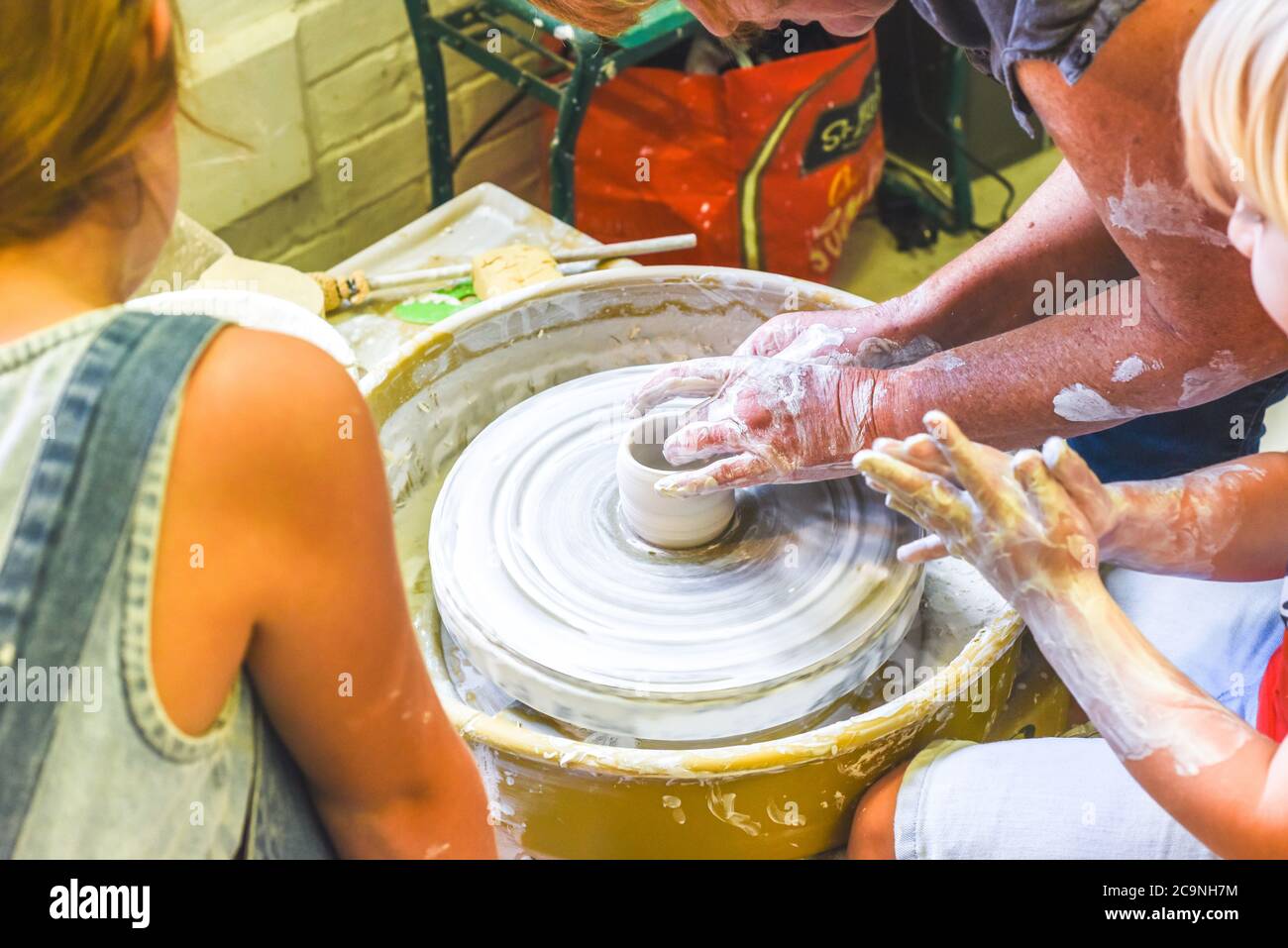 Children learning to make pottery as a hobby with their grandmother in