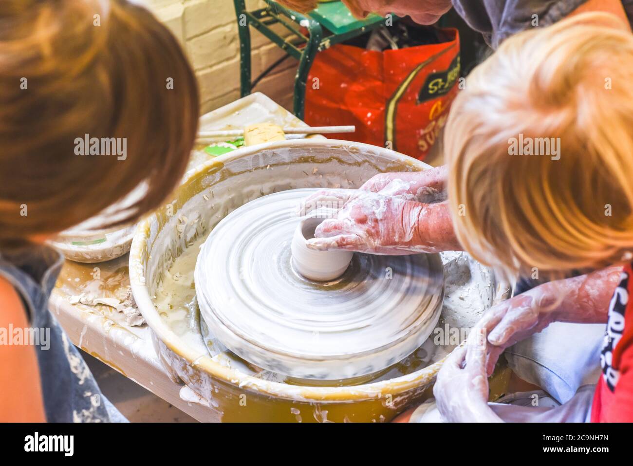 Children learning to make pottery as a hobby with their grandmother in