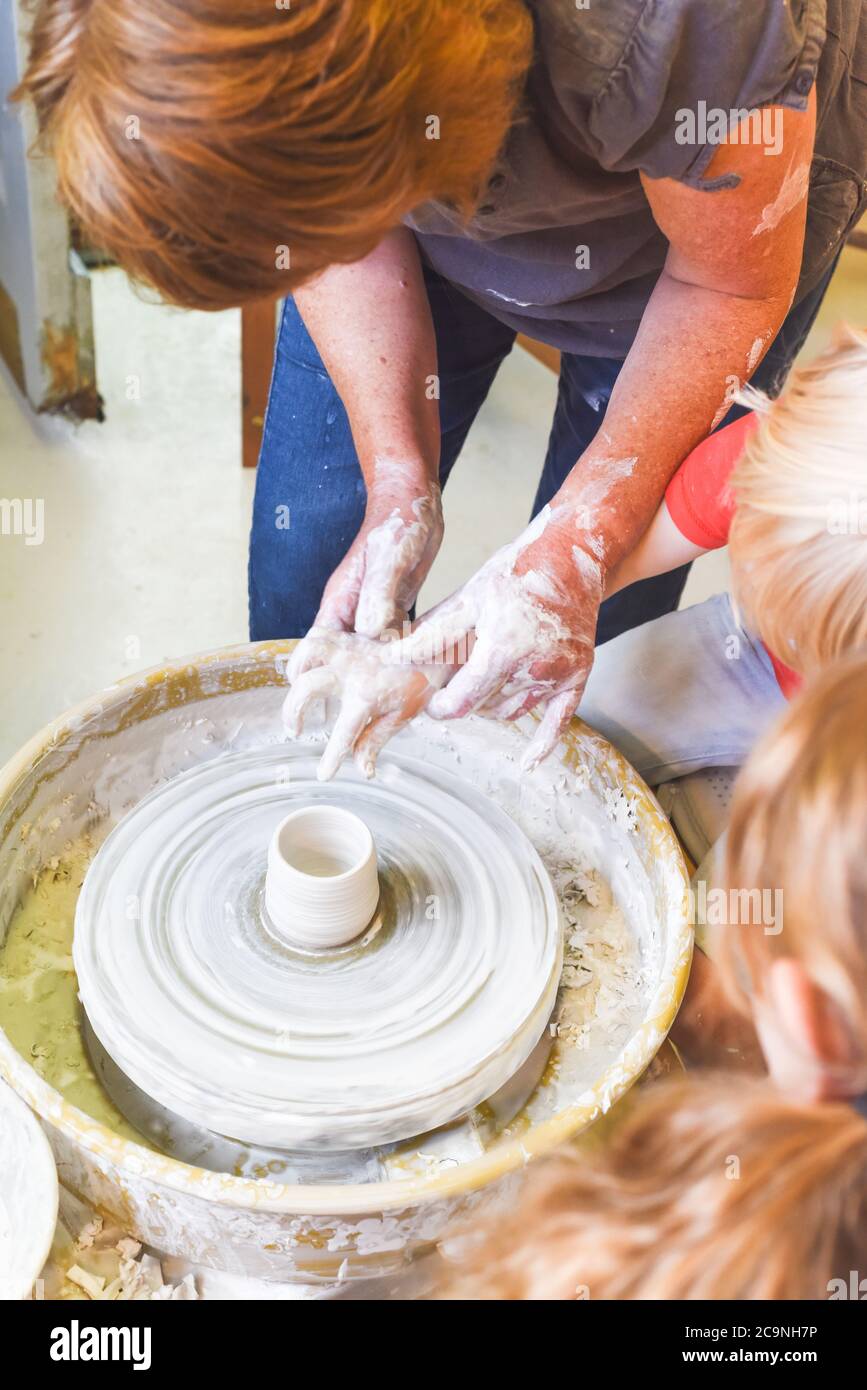 Children learning to make pottery as a hobby with their grandmother in