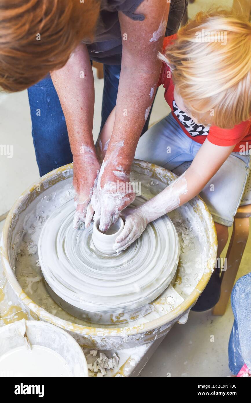 Children learning to make pottery as a hobby with their grandmother in