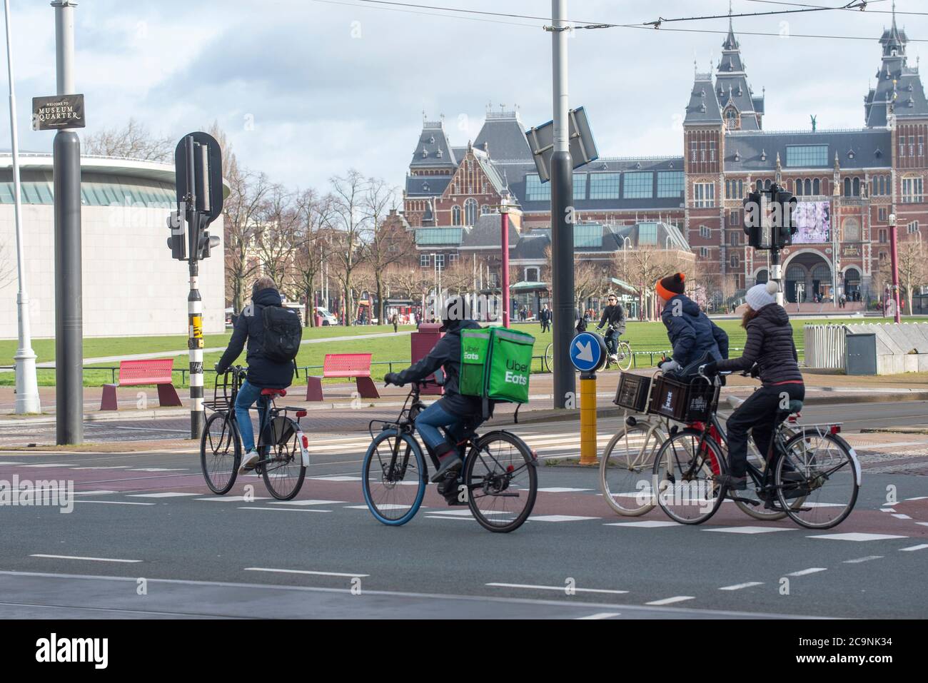 An Uber Eats rider deliveries food via bicycle in Amsterdam, Netherlands. Famed Rijksmuseum is in background. Stock Photo