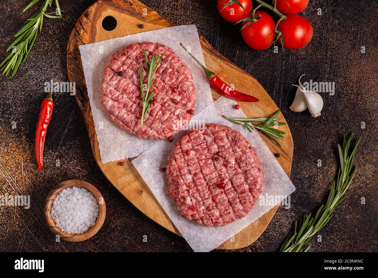 Fresh raw minced homemade grill beef burgers on wooden chopping board