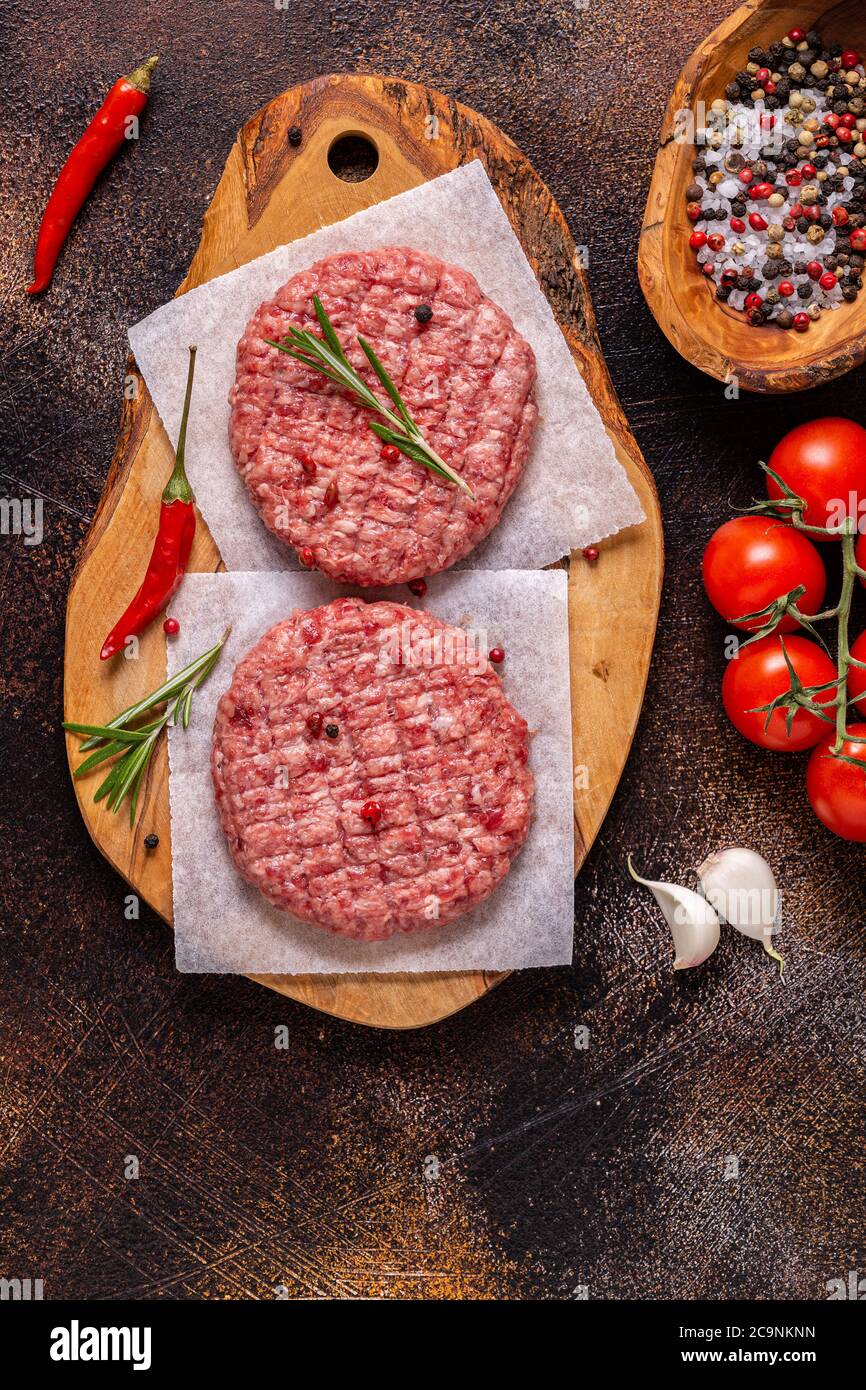 Fresh raw minced homemade grill beef burgers on wooden chopping board