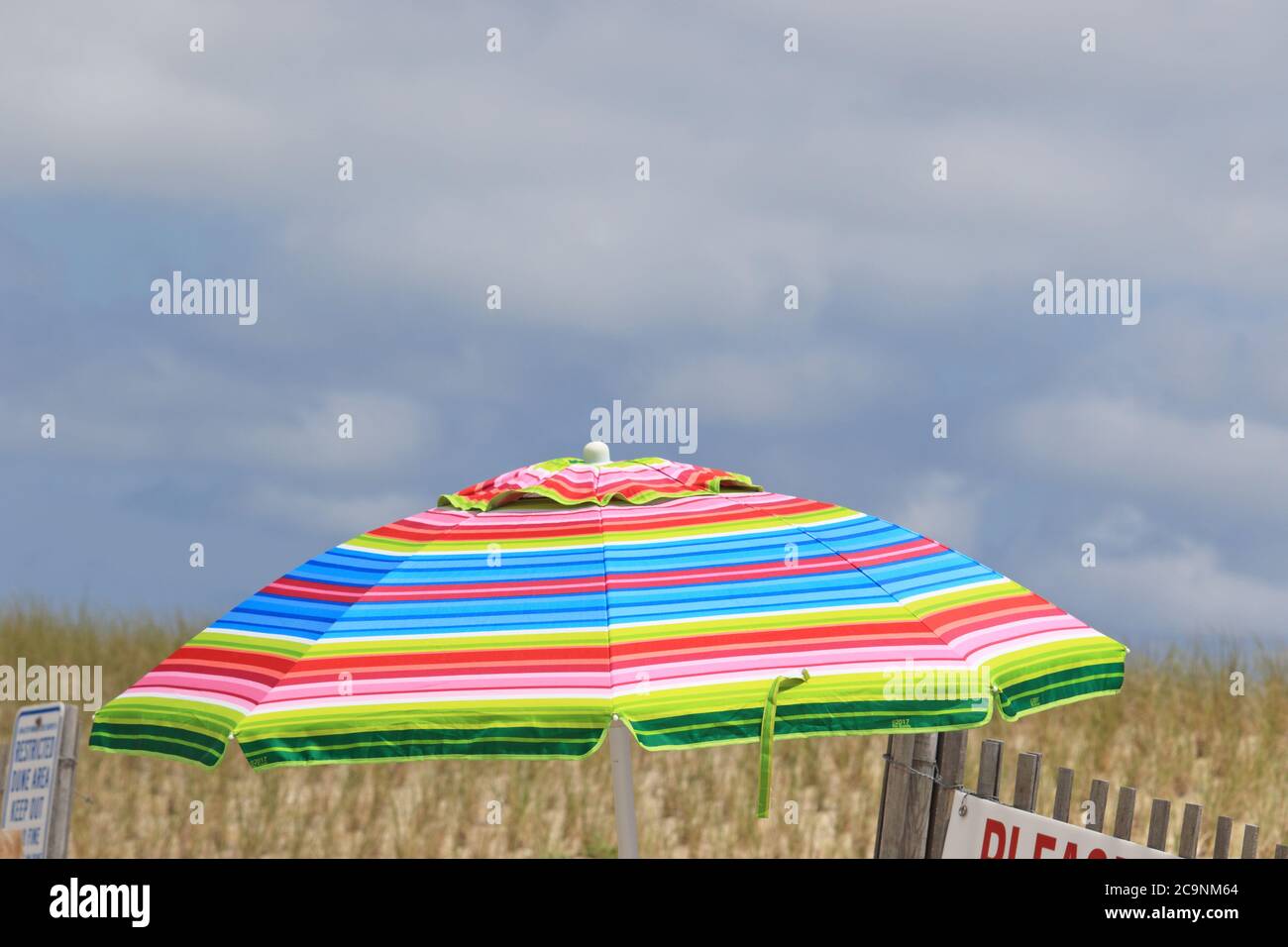 A colorful beach umbrella next to a dune in Lavallette, New Jersey, USA Stock Photo