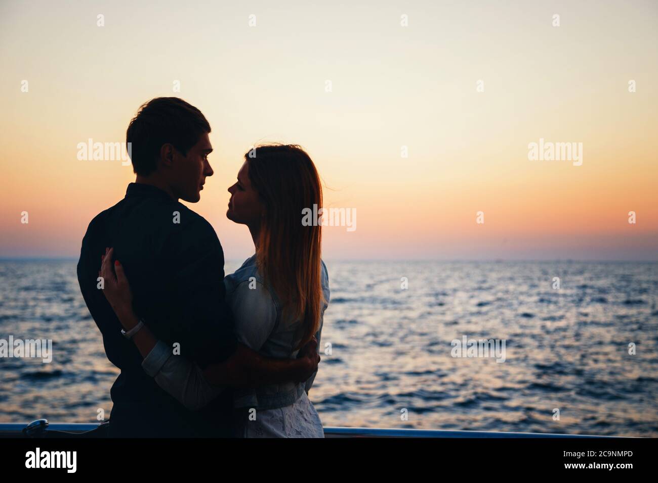 Silhouette of a couple at the beach at sunrise sky summer time ...