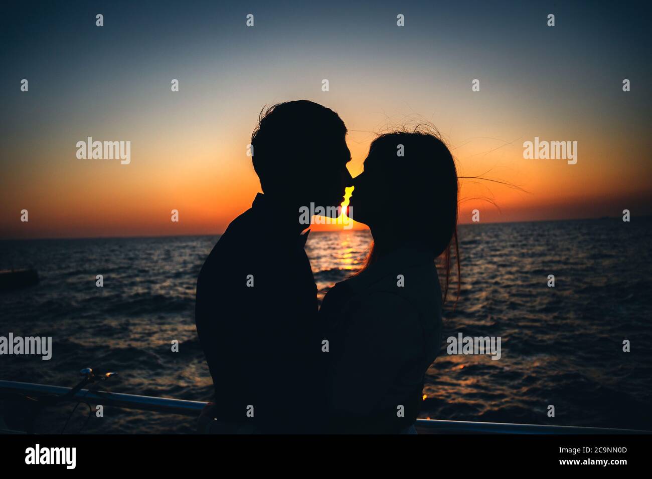 Silhouette of a couple at the beach at sunrise sky summer time ...