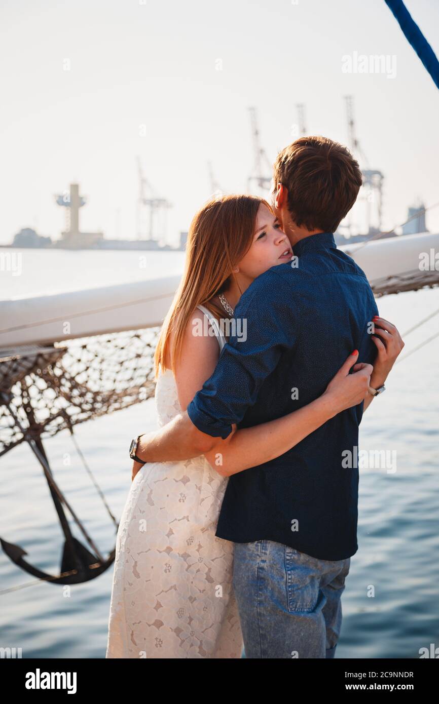 Cute young beautiful couple hugging at pier at port with small yachts, hipsters Stock Photo