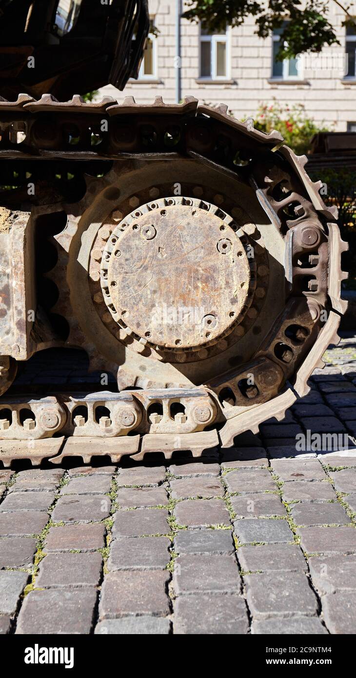 Close up picture of excavator track shoe on a cobblestone street, selective focus. Stock Photo