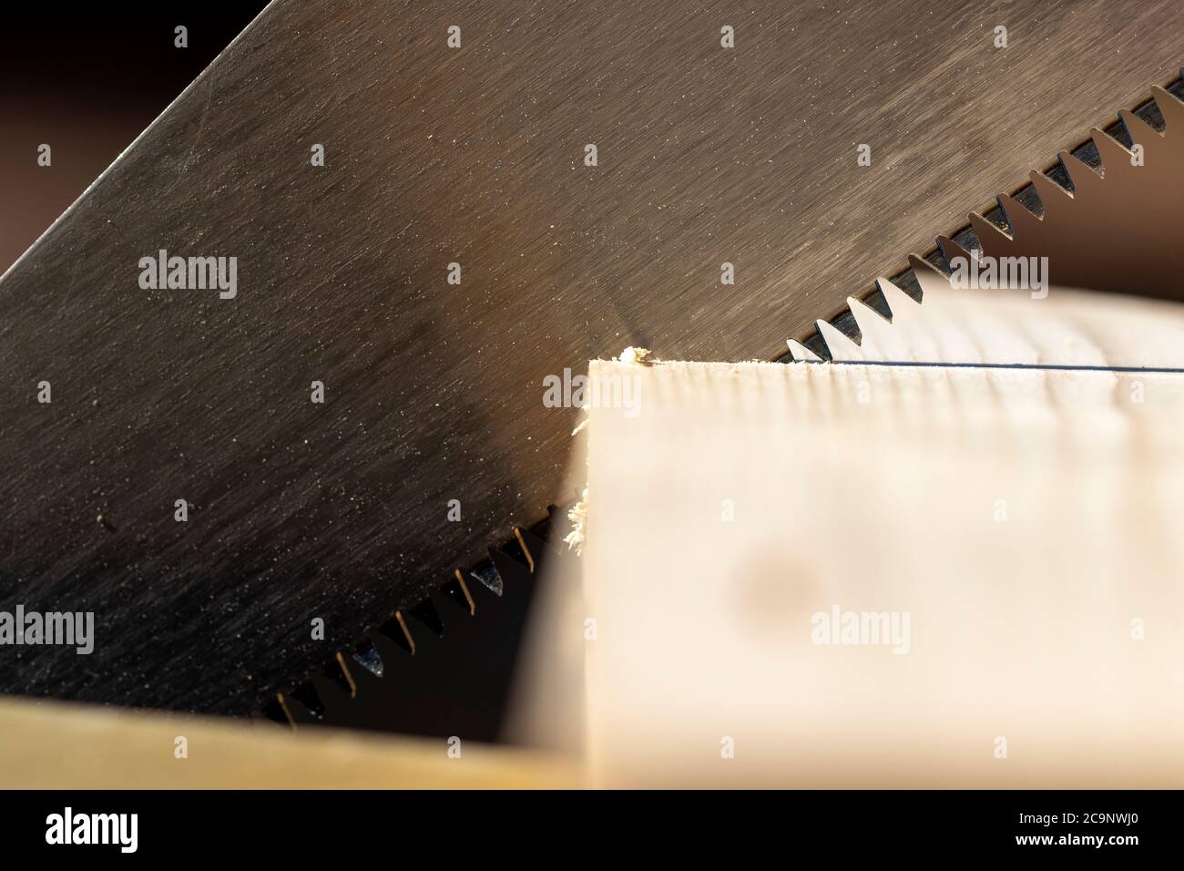 A closeup portrait of a wooden plank being sawn by a wood cutting hand