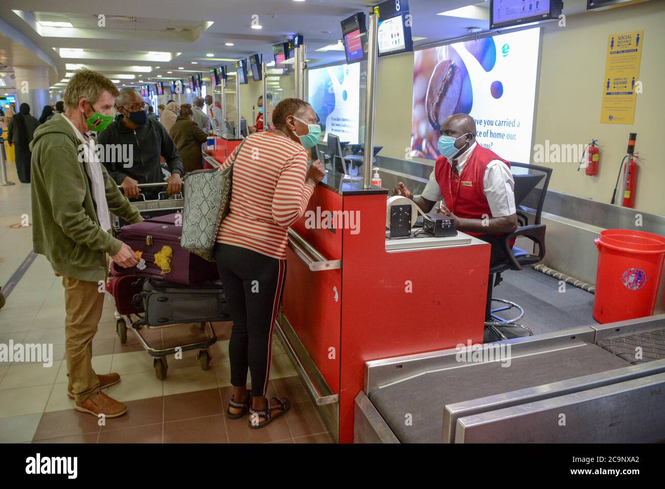 Passengers wearing face masks queue at checkin desks at Jomo Kenyatta
