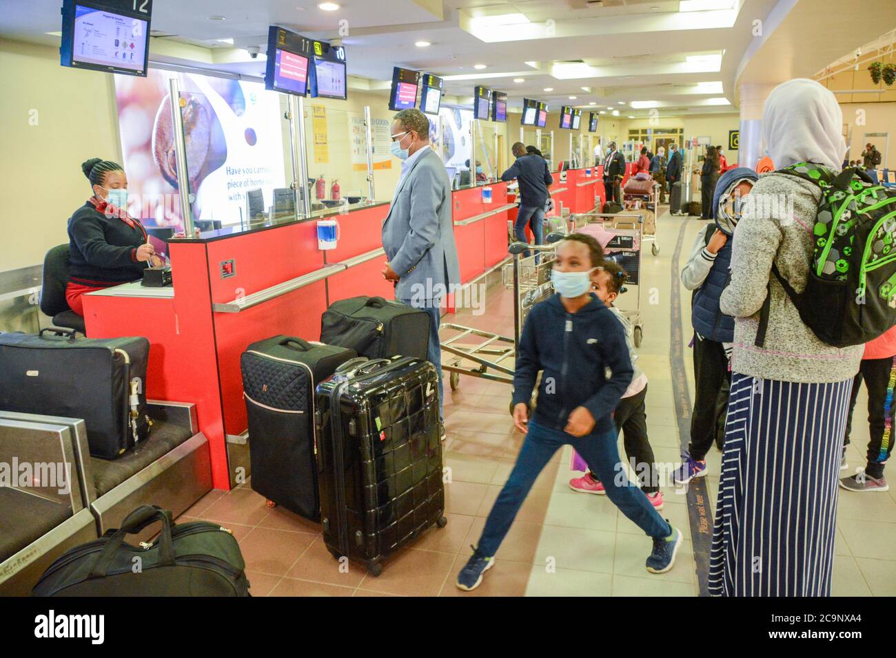 Passengers wearing face masks queue at checkin desks at the Jomo