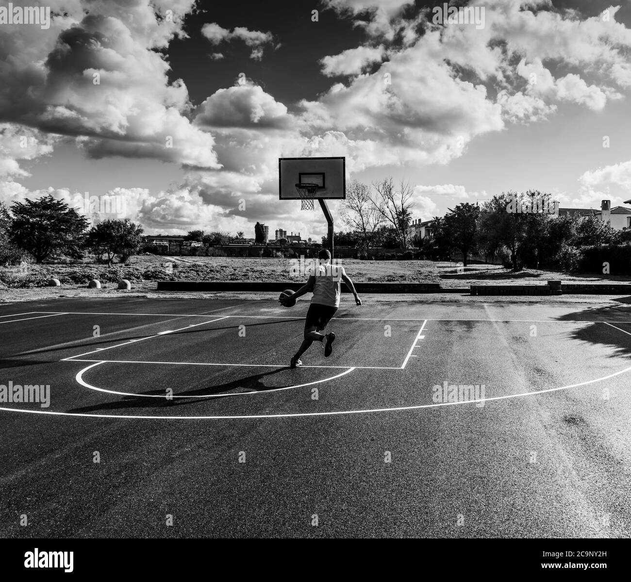 Basketball player driving to the basket seen from behind in black and