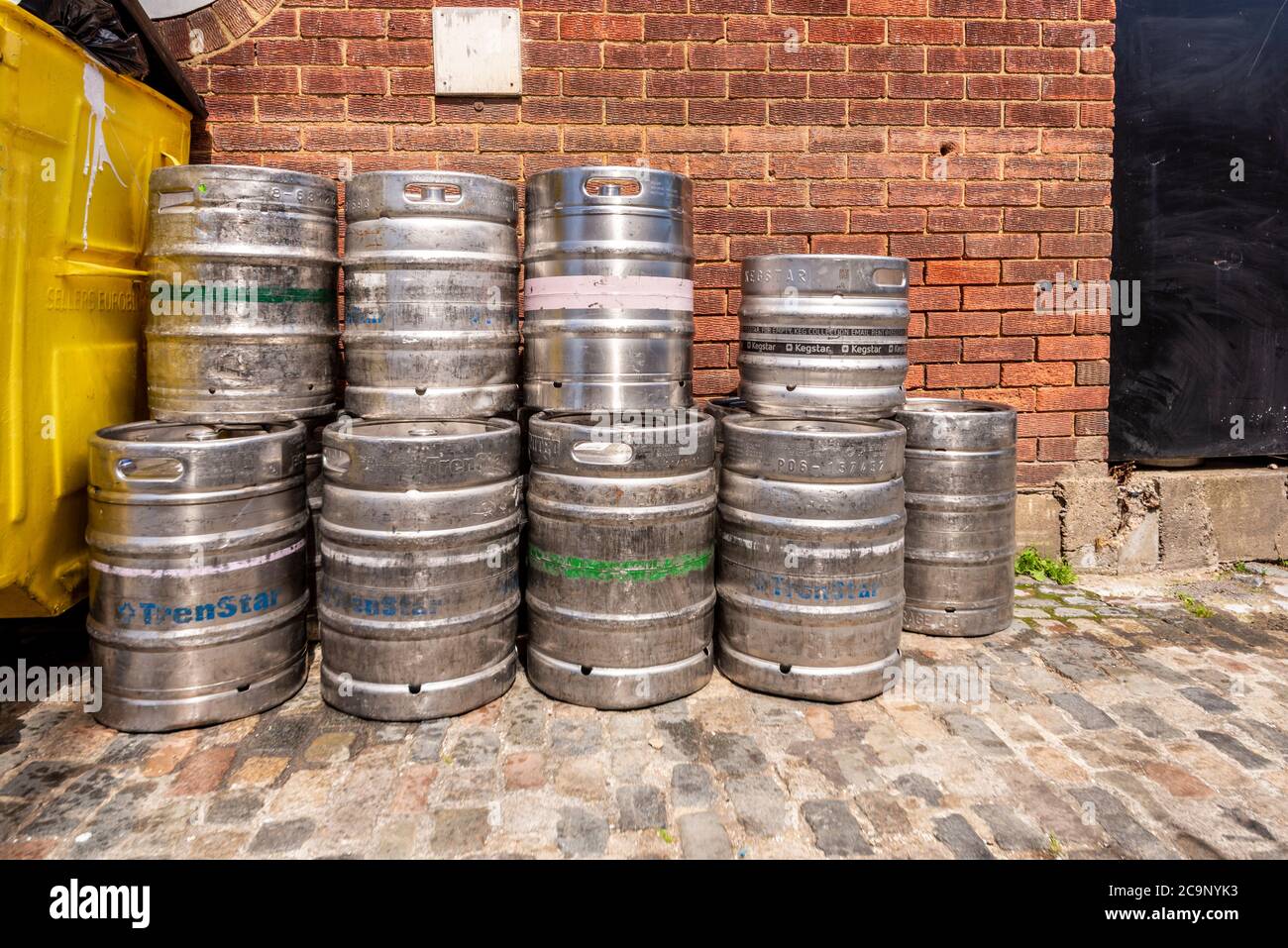 Stacks of empty stainless beer barrels with rubbish bin at rear of pub in Old Leigh, Leigh on Sea, Essex, UK, in July during COVID-19. Waste bin Stock Photo