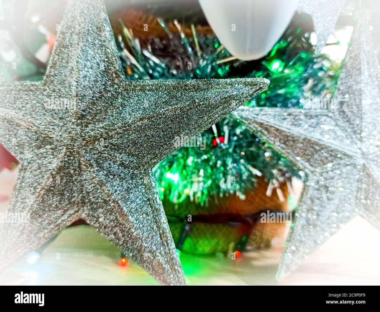 Close up of Silver stars on a Christmas tree with green lights on the ...