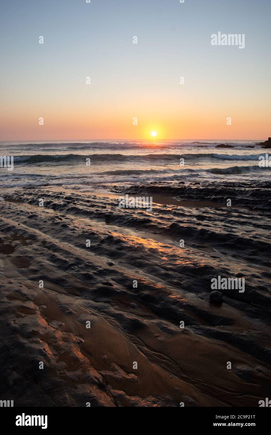 Rocks on the beach in the evening, the sun is hiding in the horizon, north of Spain Stock Photo