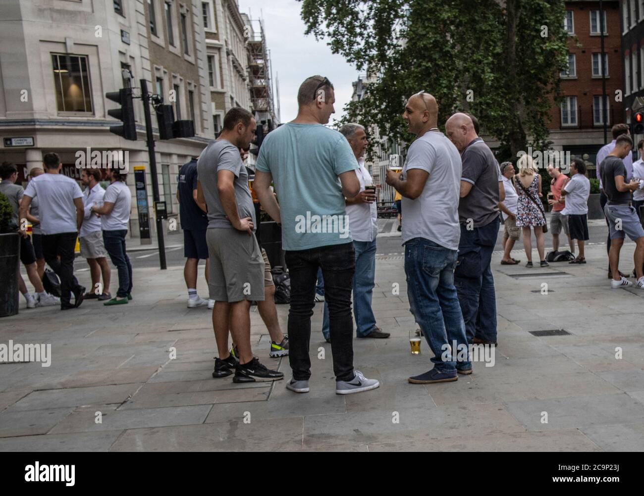 City workers enjoy drinking at the Sugarloaf pub whilst outside socially distanced on a summers Friday evening on Queen Street, London, EC4 Stock Photo