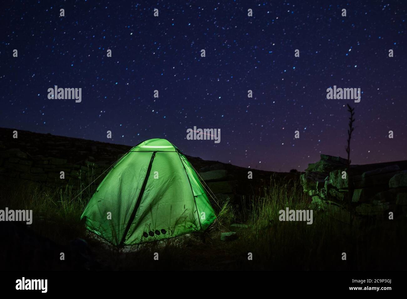 Camping tent near the Dinara mountain -highest point of Croatia in the Dinaric Alps with light inside is on the mountain valley under night starry sky Stock Photo