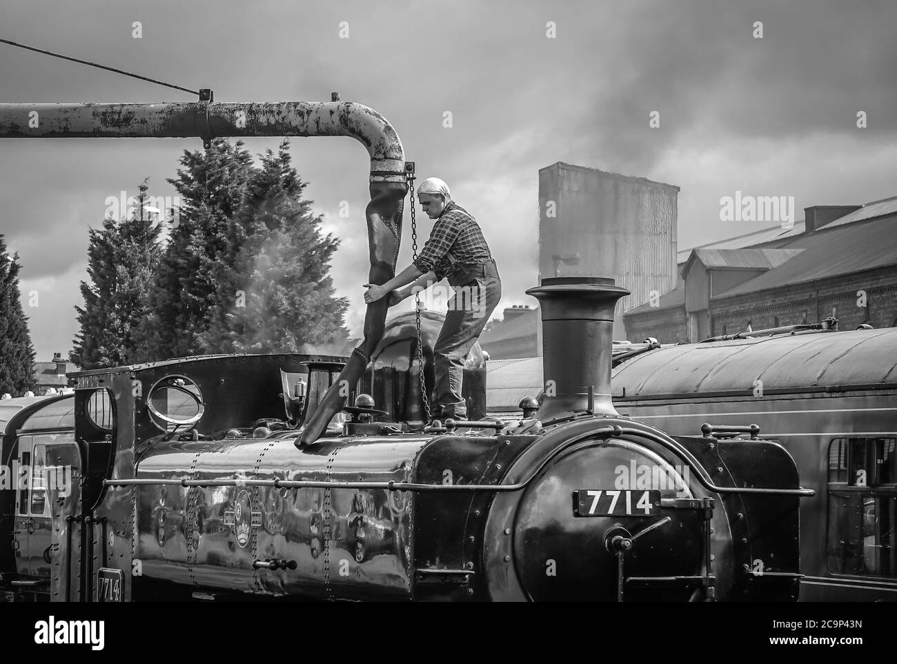 Steam train crew fireman filling water tank of vintage steam locomotive 7714, Severn Valley heritage steam railway, Kidderminster UK. Stock Photo