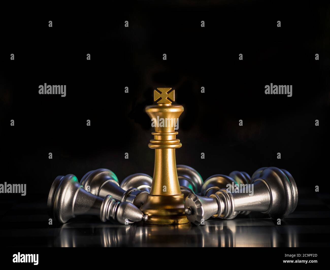 Golden king chess is surrounded by falling around silver chess pieces  to fighting with teamwork to victory, business strategy concept and leader and Stock Photo