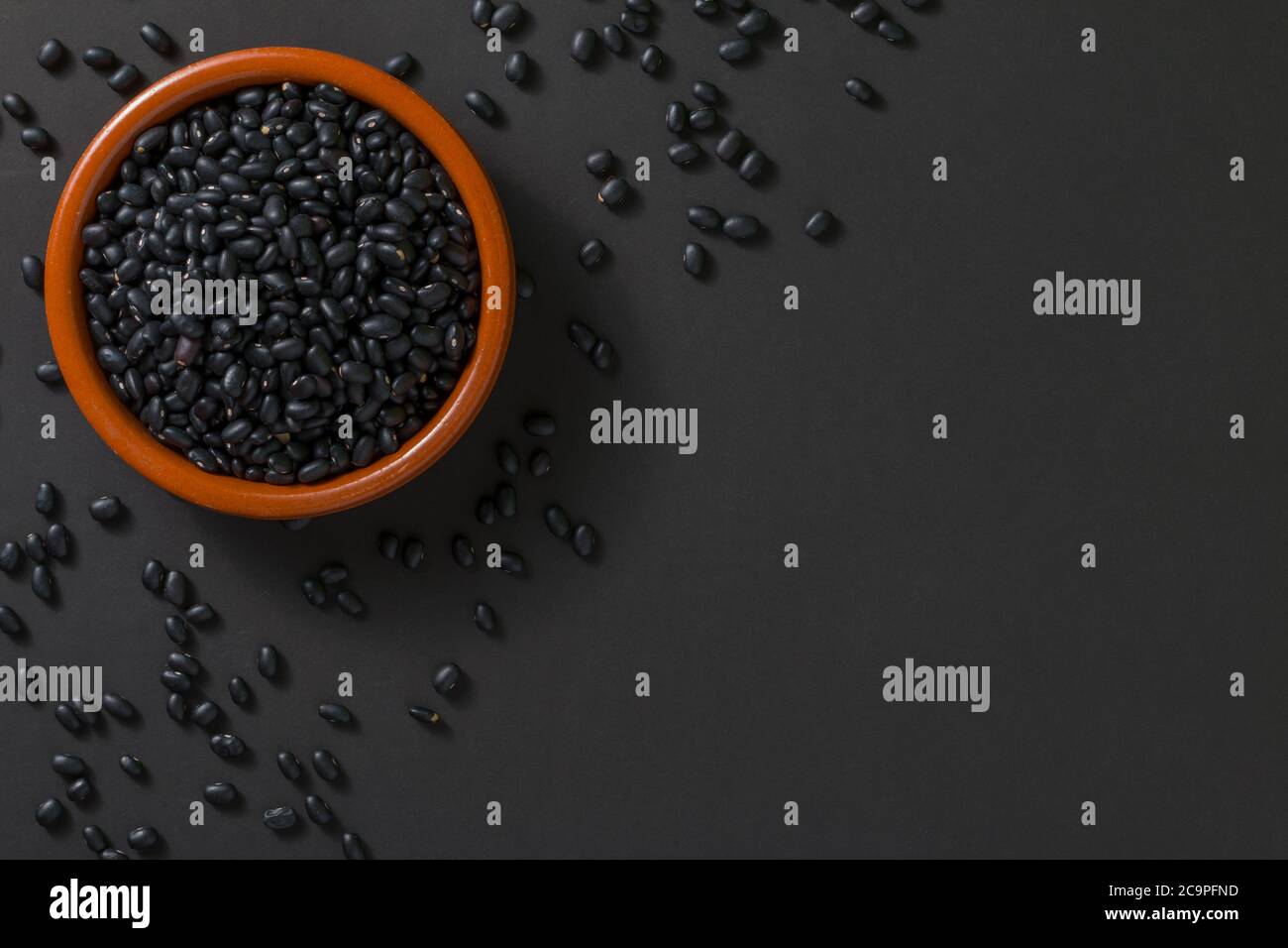 Top view of a bowl with black beans on a black background. Stock Photo