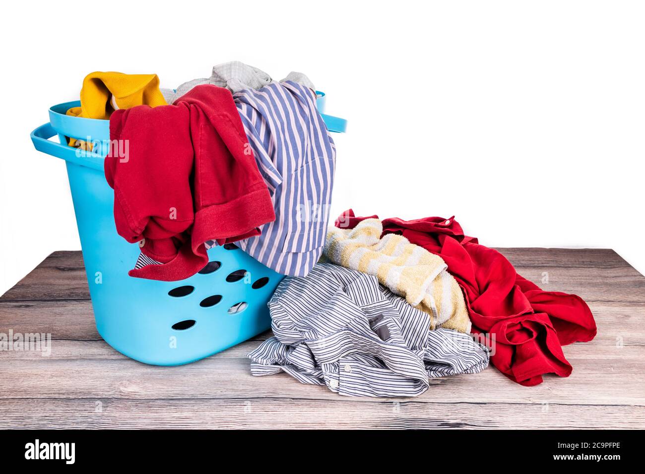 Laundry basket full of worn apparels for washing on wooden table against white background Stock Photo