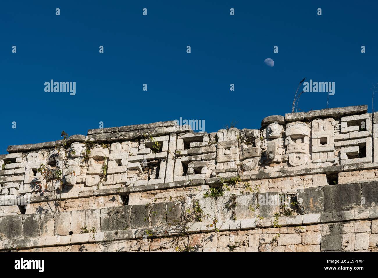 The moon rises over the Chaac masks on the roof comb of the Casa Colorado or Red House in the ruins of the great Mayan city of Chichen Itza, Mexico. Stock Photo