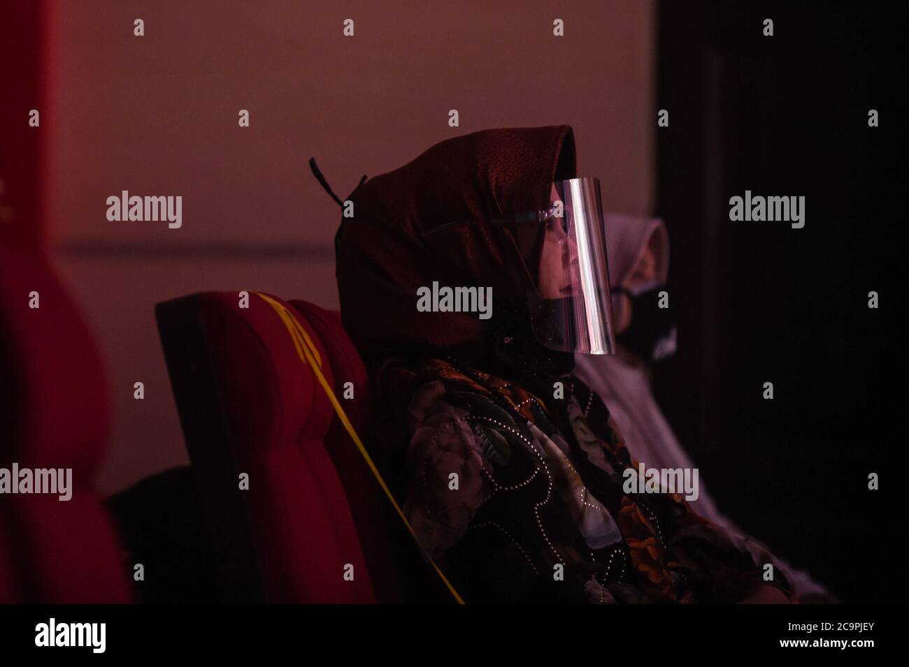 Jakarta, Indonesia. 1st Aug, 2020. A woman wearing protective face shield watches a Javanese human puppet show by the Wayang Orang Bharata troupe with limited on-site audience amid the COVID-19 outbreak in Jakarta, Indonesia, Aug. 1, 2020. The performance was also live streamed as a fundraiser to encourage Javanese human puppet show enthusiasts to help the troupe's actors and their families overcome current financial struggles. Credit: Agung Kuncahya B./Xinhua/Alamy Live News Stock Photo