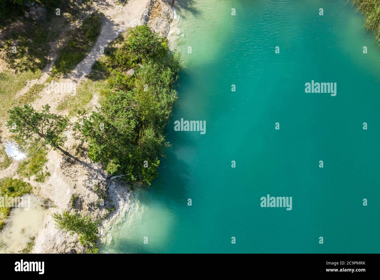 aerial top view of quarry lake with clear turquoise water and green trees ashore Stock Photo
