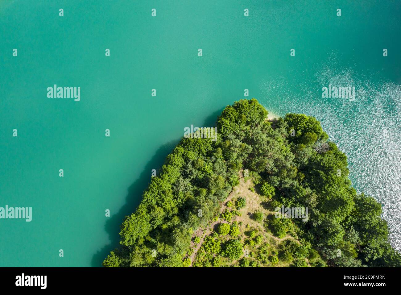 aerial top view of quarry lake and island with green forest on a sunny
