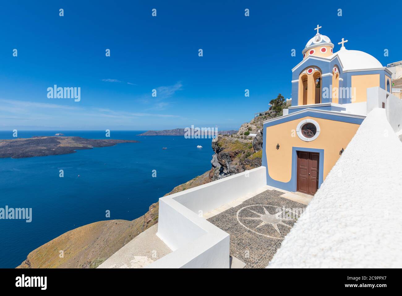Sunny travel landscape, belltower of a church with a view of Santorini volcanic caldera and ships in it, Santorini, Cyclades, Greece Stock Photo