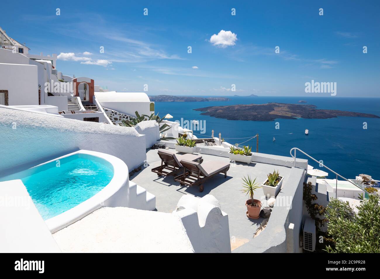 Swimming poolside, infinity pool relaxation view out over the sea caldera of Santorini Greece. Luxury travel, summer holiday vacation, peaceful resort Stock Photo