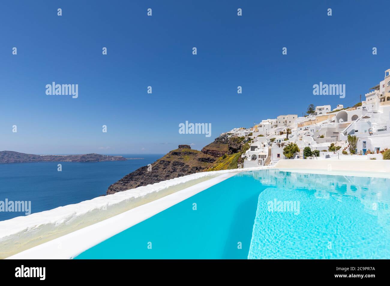 Swimming poolside, infinity pool relaxation view out over the sea caldera of Santorini Greece. Luxury travel, summer holiday vacation, peaceful resort Stock Photo